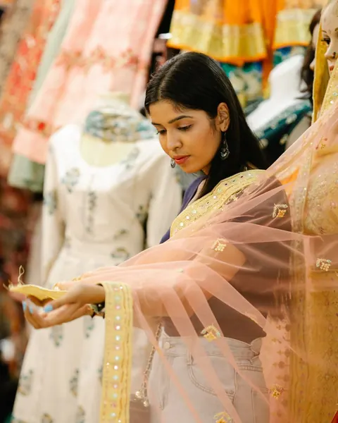 A woman looking at an embroidered dupatta in a clothing shop