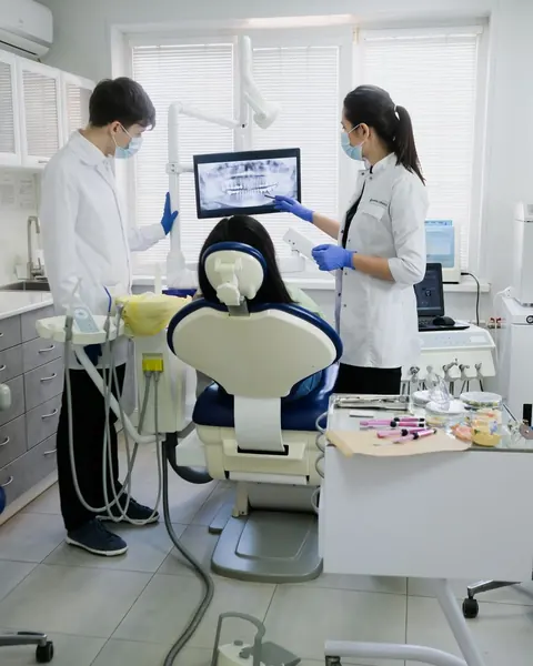 Two dentists with a patient in a bright clinic