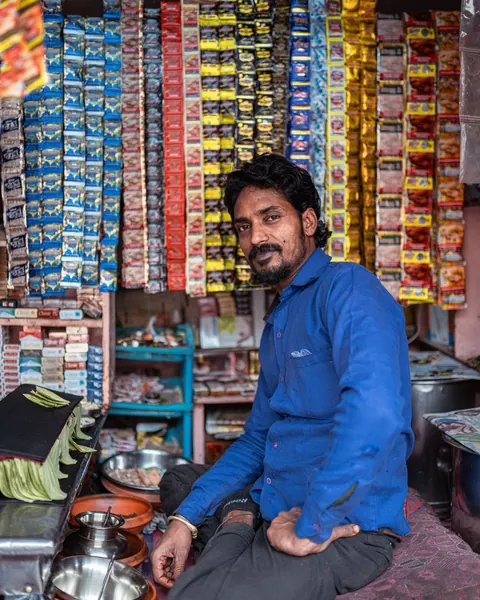 A shop owner sitting among the goods in his shop